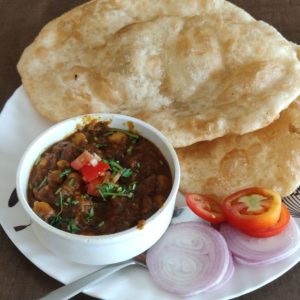 Chole Bhature or Chick pea curry Chole Bhature or Chick pea curry and Fried Puri served in terracotta crockery over white background. selective focus